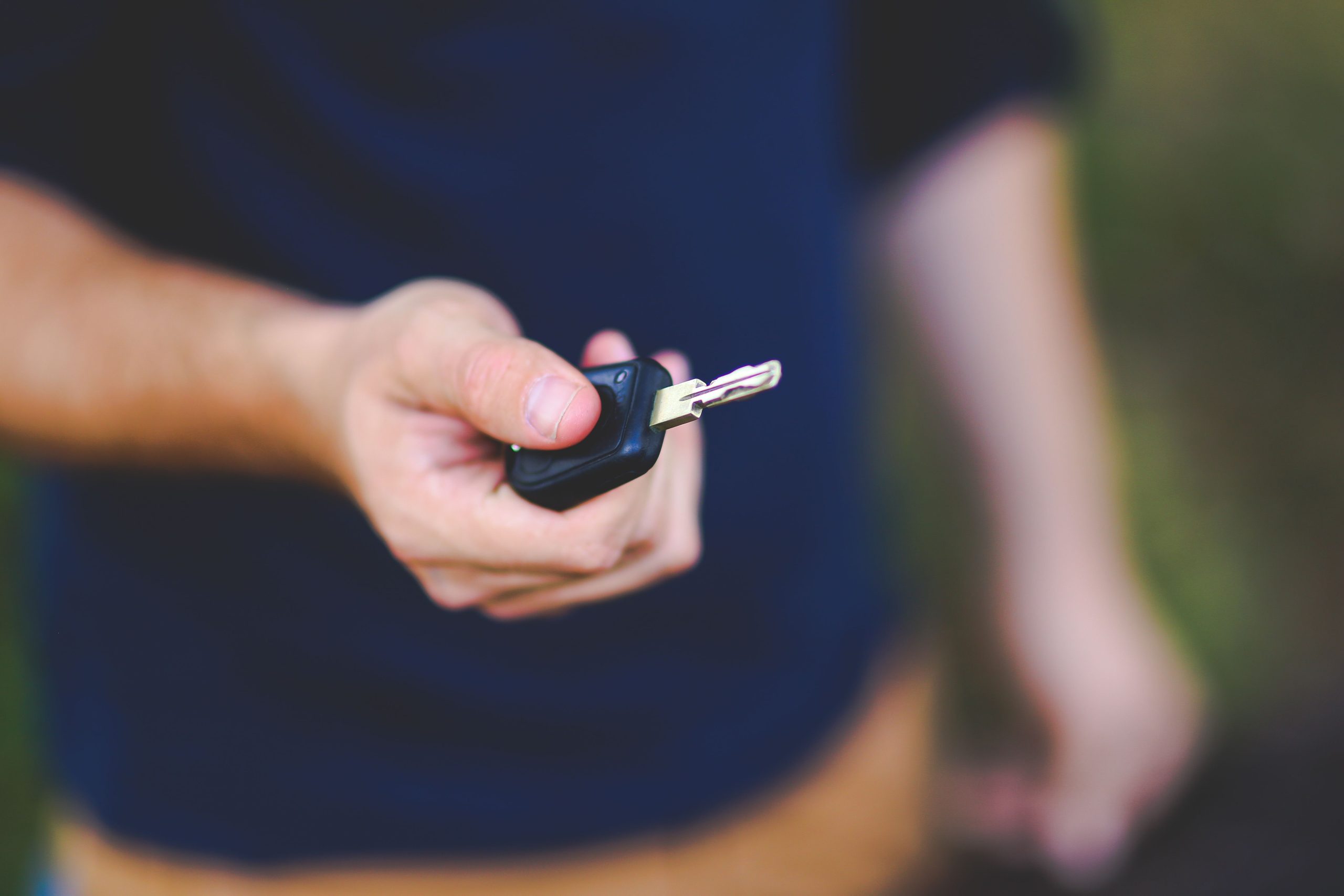 Hand holding out a car key for another person to take