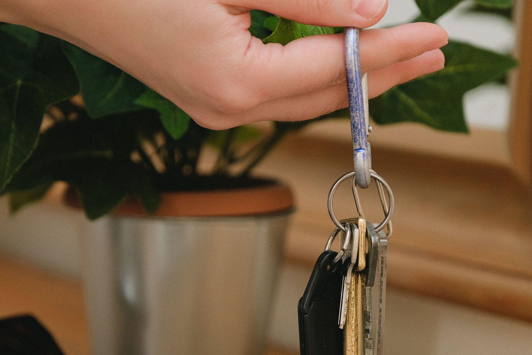 Hand holding a ring of several metal keys above an office desk